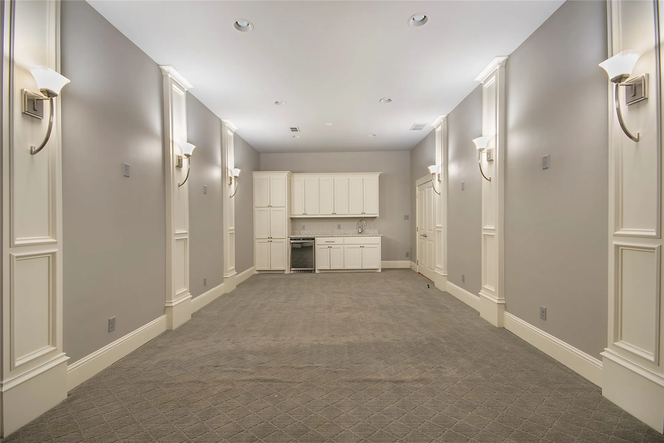 Recessed lighting, wall sconces, built-in cabinetry, integrated beverage refrigerator, and patterned carpet flooring