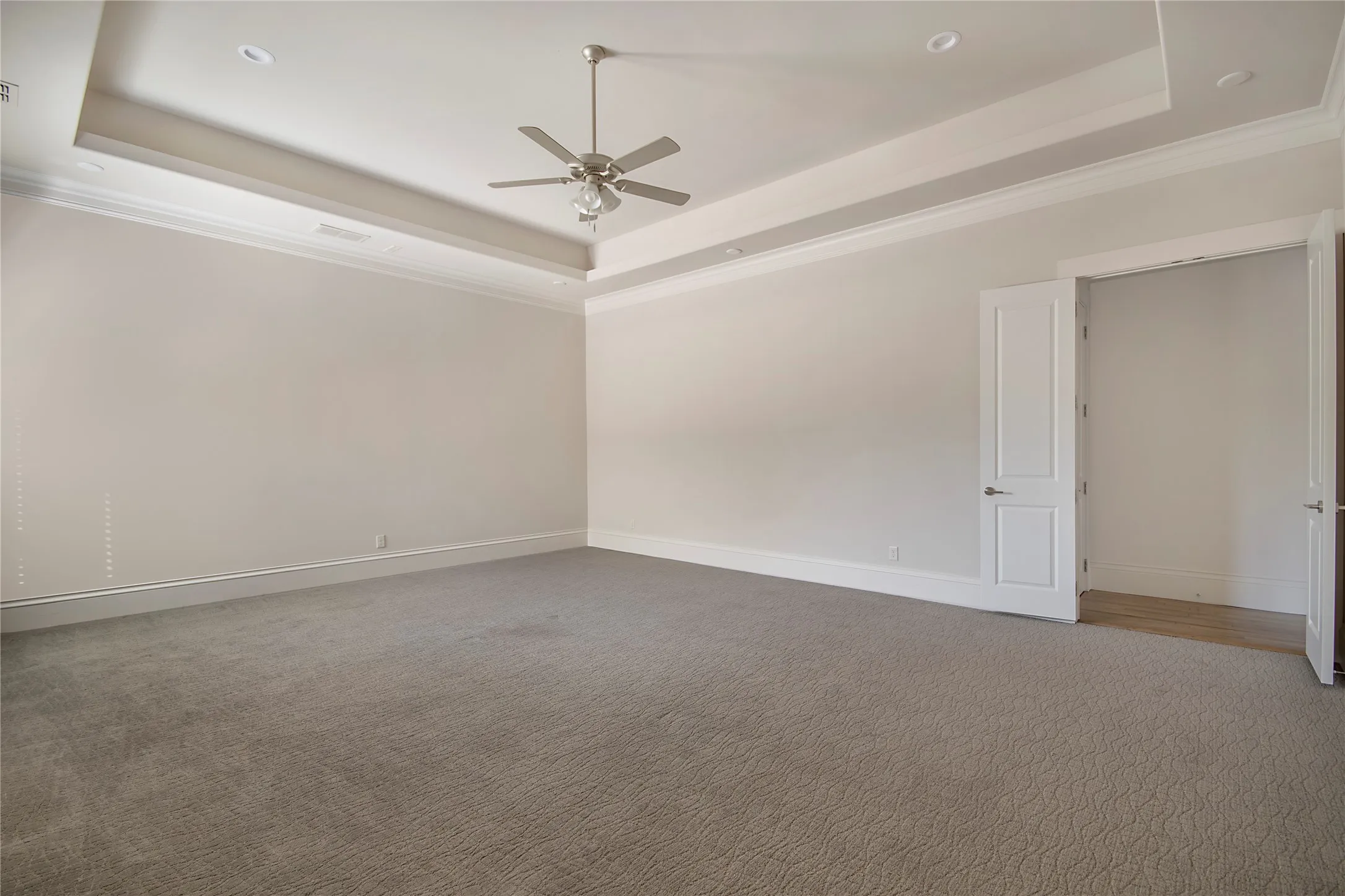 Recessed lighting, ceiling fan, tray ceiling, crown molding, and neutral-toned carpeting