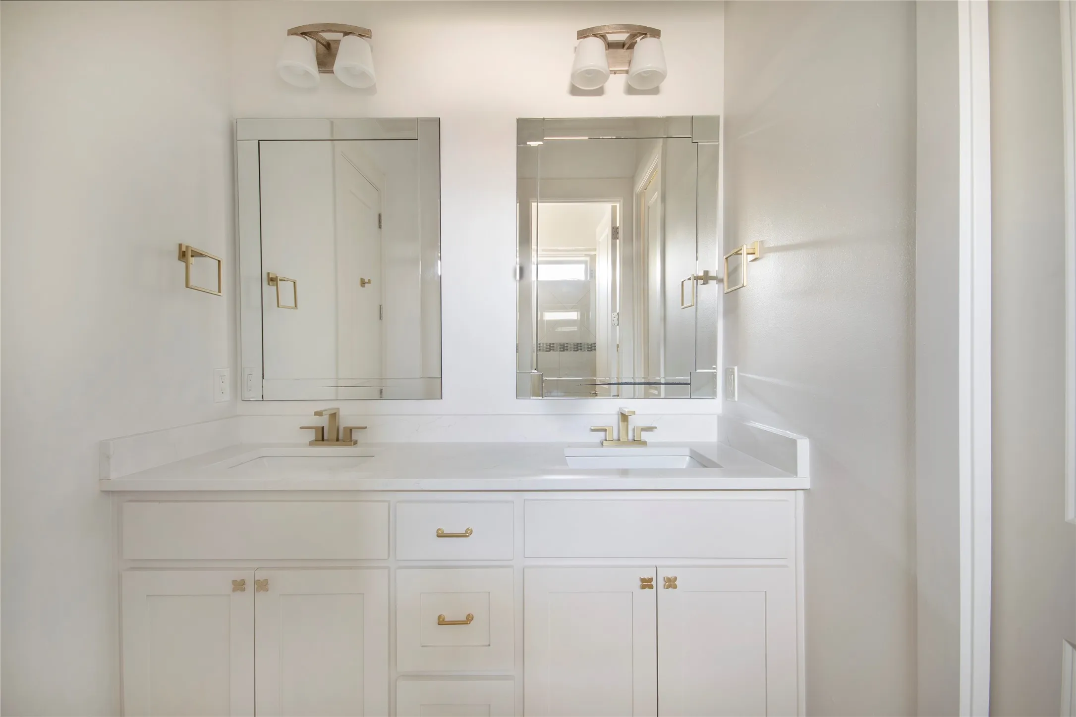 Dual vanity with white cabinetry, gold-toned hardware, and rectangular undermount sinks