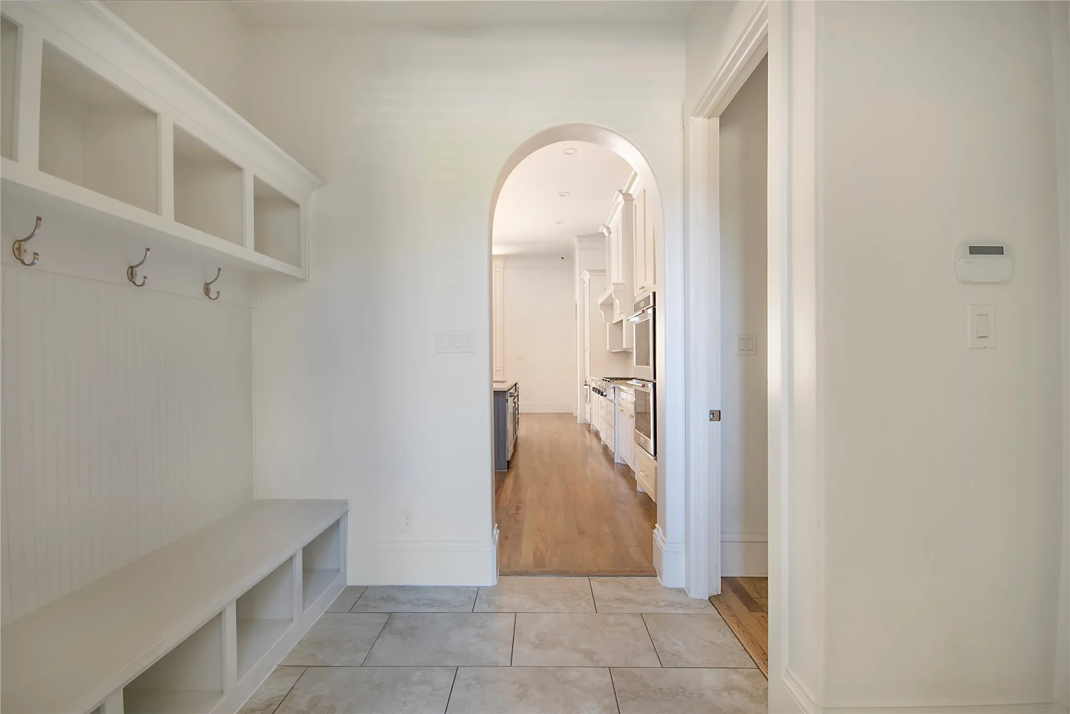 Built-in bench with storage, beadboard paneling, and an arched entryway