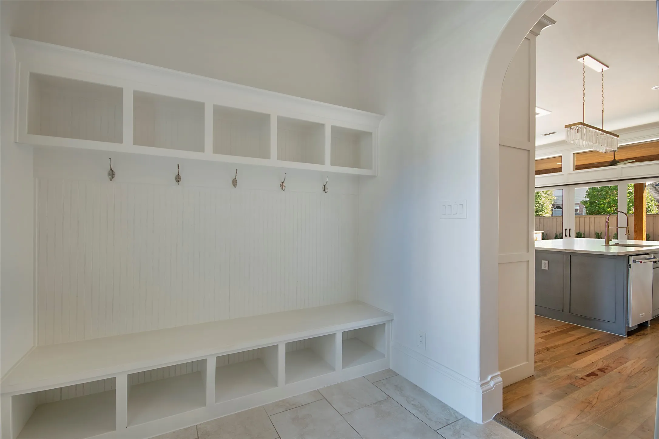 Built-in hall tree with storage cubbies and hooks, natural wood flooring, archway entry, recessed lighting, and a contemporary chandelier