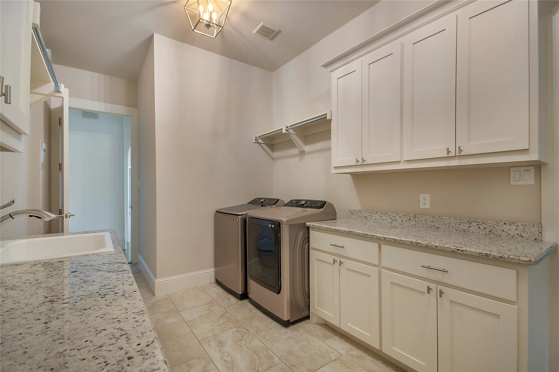 Light-toned cabinetry with stainless steel hardware, a utility sink with a pull-down faucet, and a light-toned countertop
