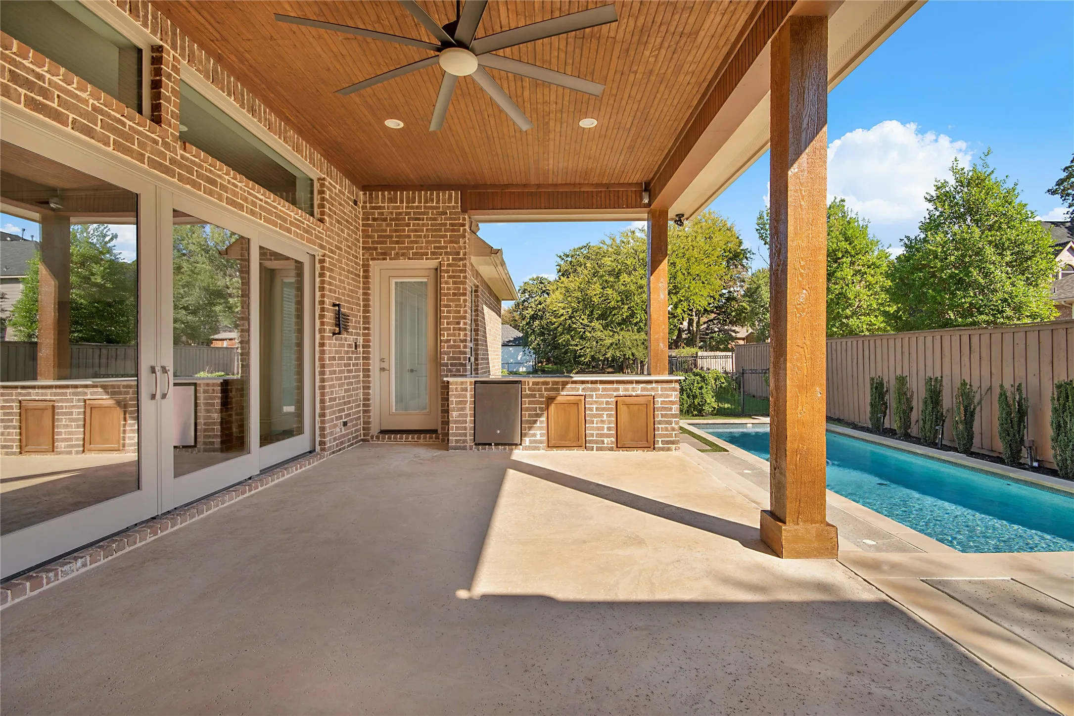 Covered outdoor patio with a wood-plank ceiling and ceiling fan
