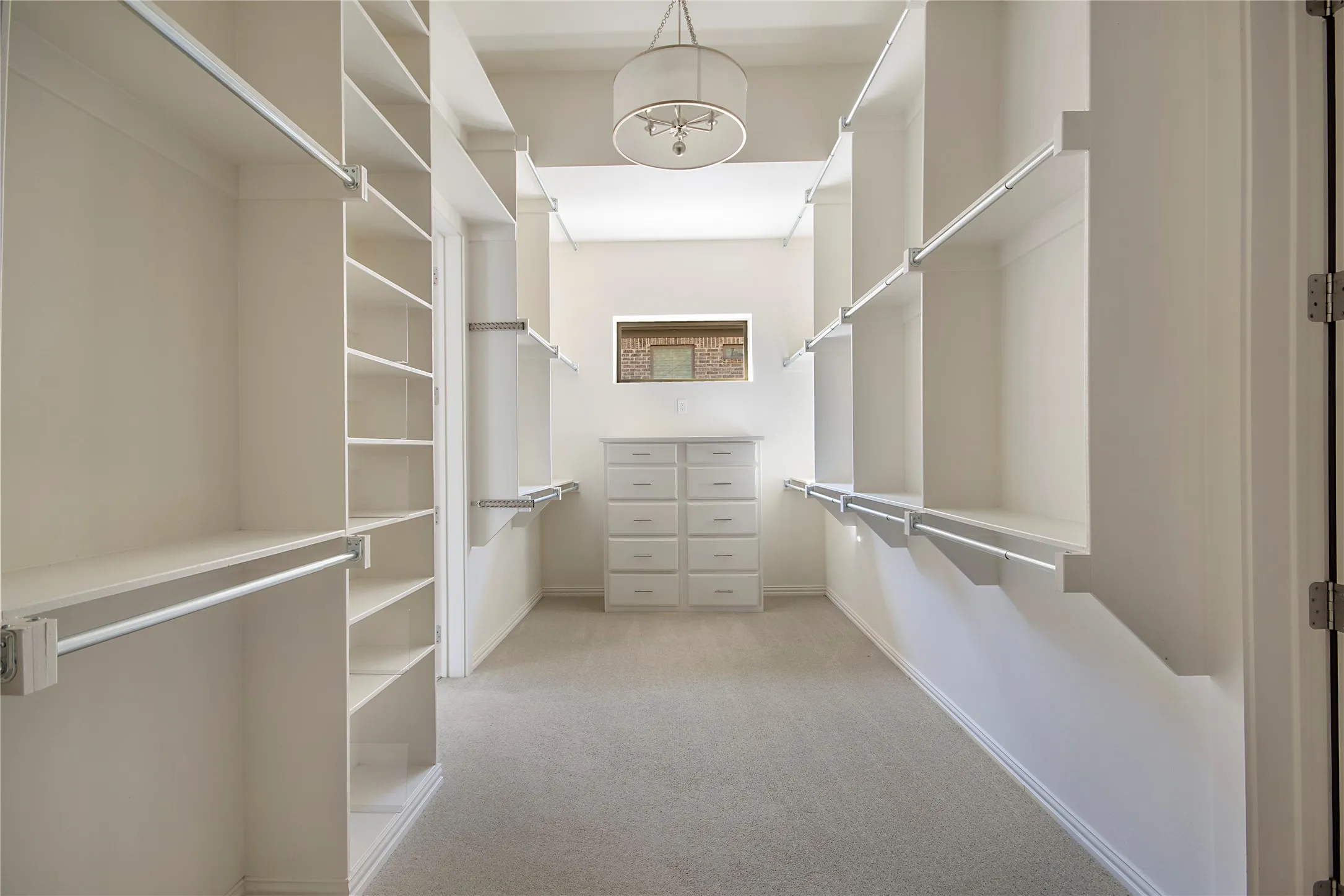 Walk-in closet with extensive built-in shelving, multiple hanging rods, a built-in dresser, and a central light fixture