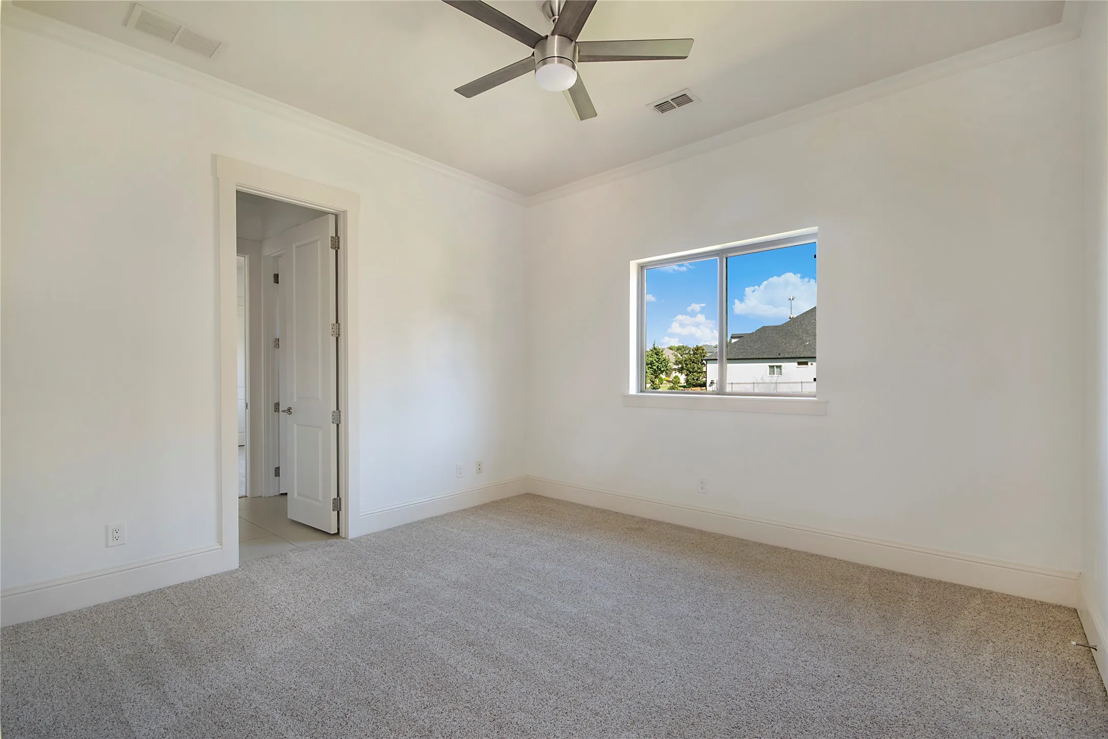 Neutral tone carpeting, white walls, crown molding, and a ceiling fan with integrated lighting