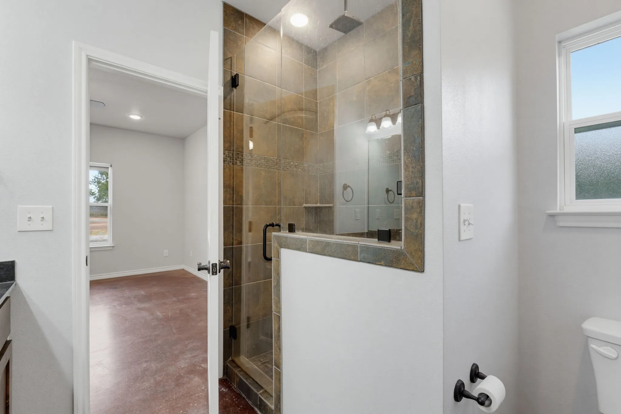 Tile-surround walk-in shower with glass enclosure, rain shower head, and built-in shelving