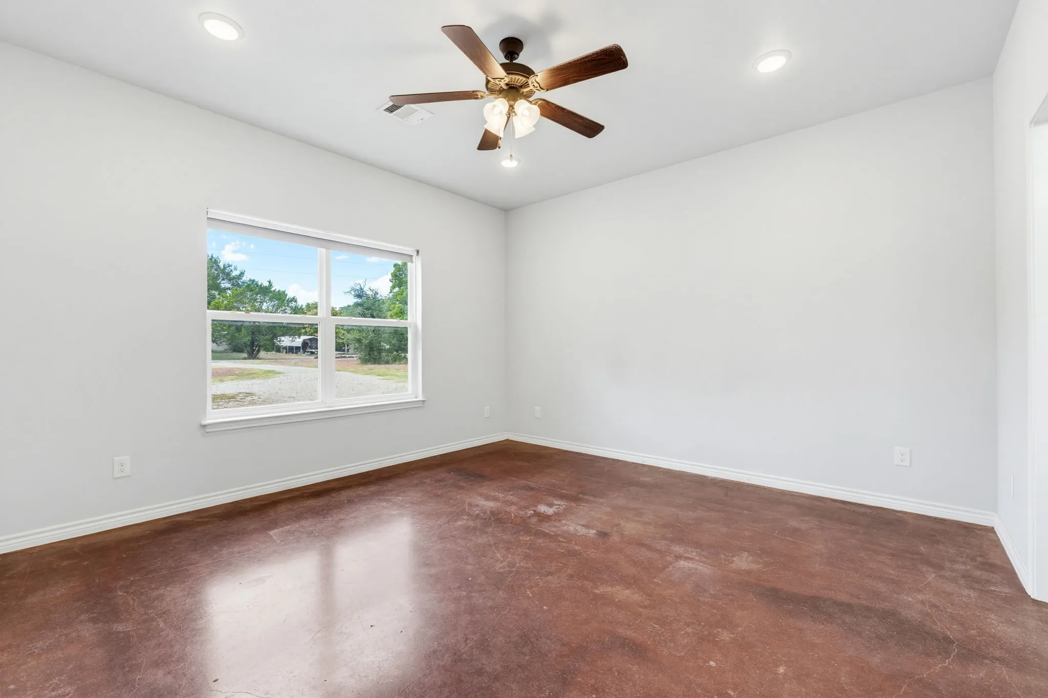 Expansive interior featuring stained concrete flooring, recessed lighting, a ceiling fan, and a large window