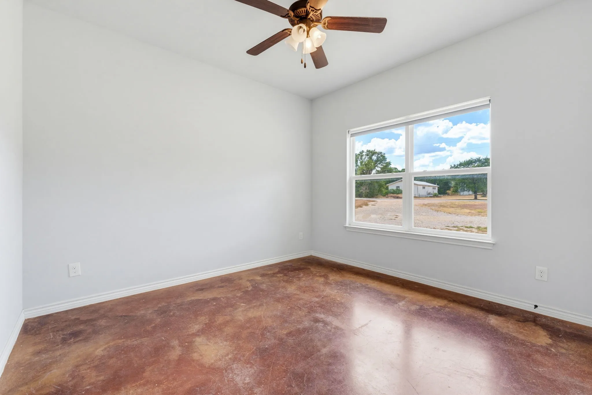 Neutral wall paint, ceiling fan with integrated lighting, window with white trim, brown-toned flooring
