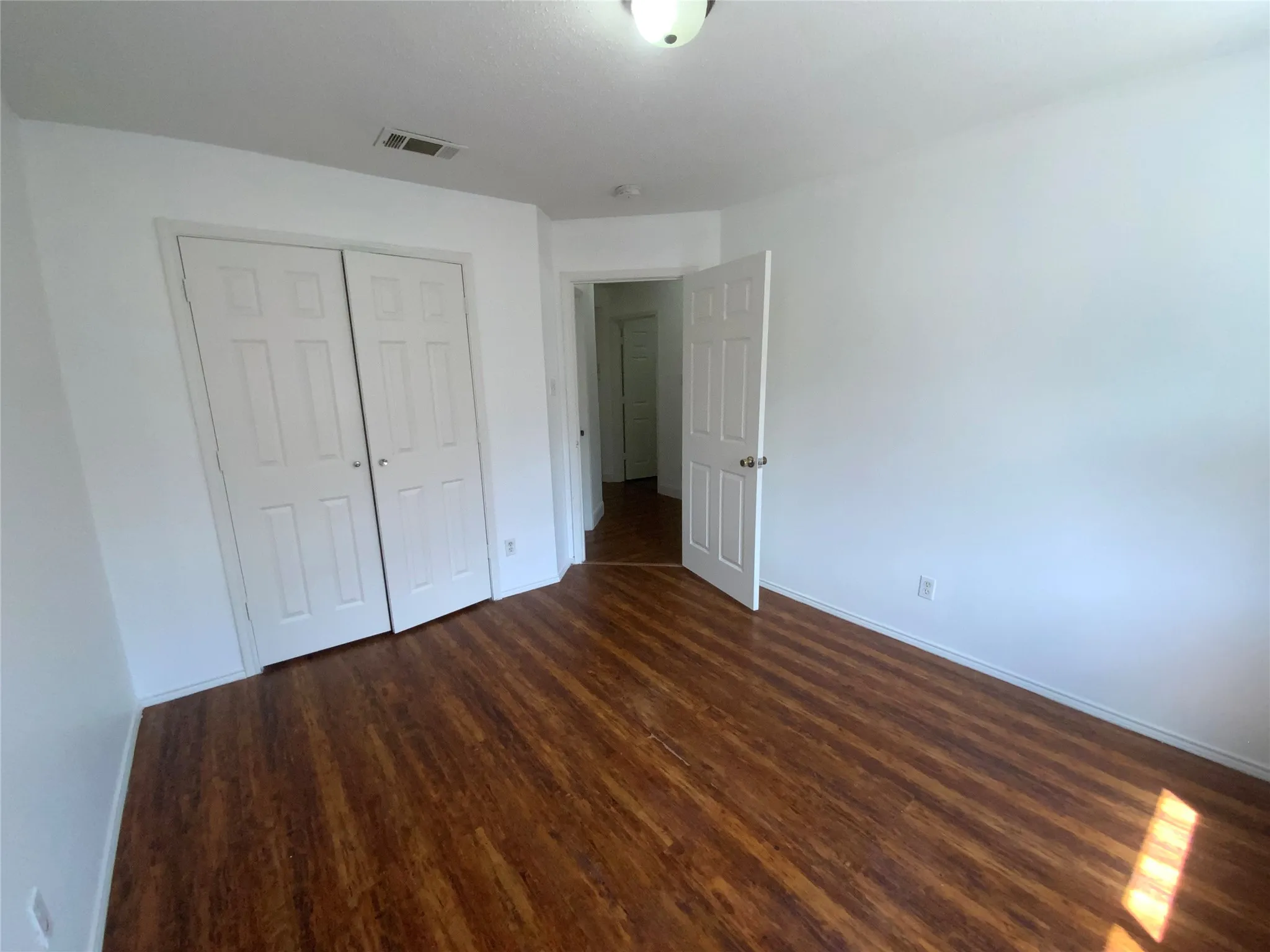 Wood-finish flooring, white walls, and a ceiling-mounted light fixture
