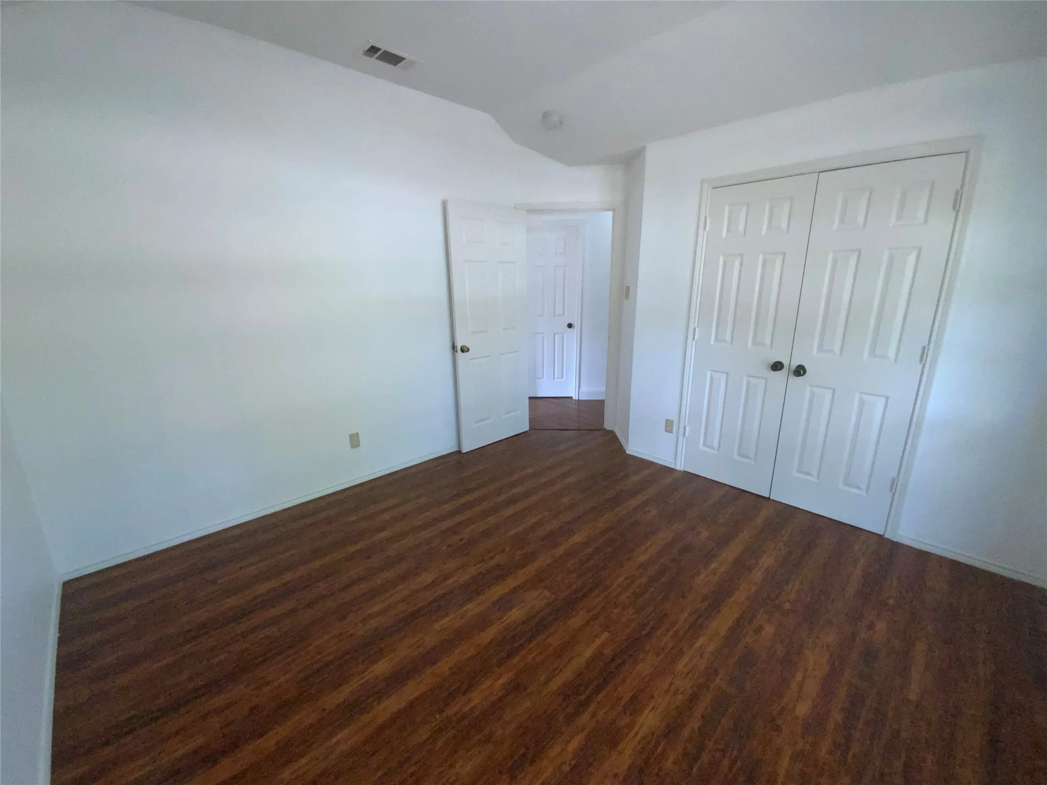 Wood-finish flooring, white walls, and a double-door closet