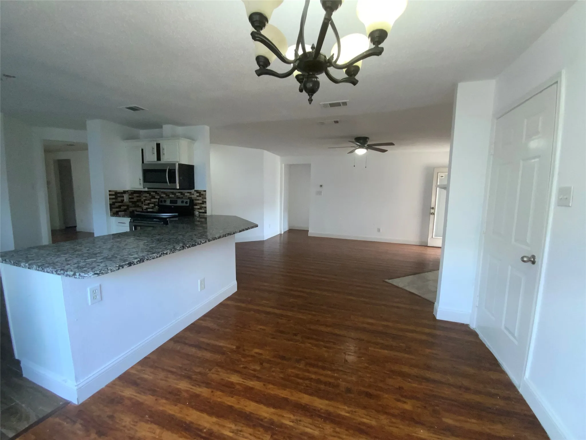 Kitchen island with stone-finish countertop, wood-finish flooring, and chandelier