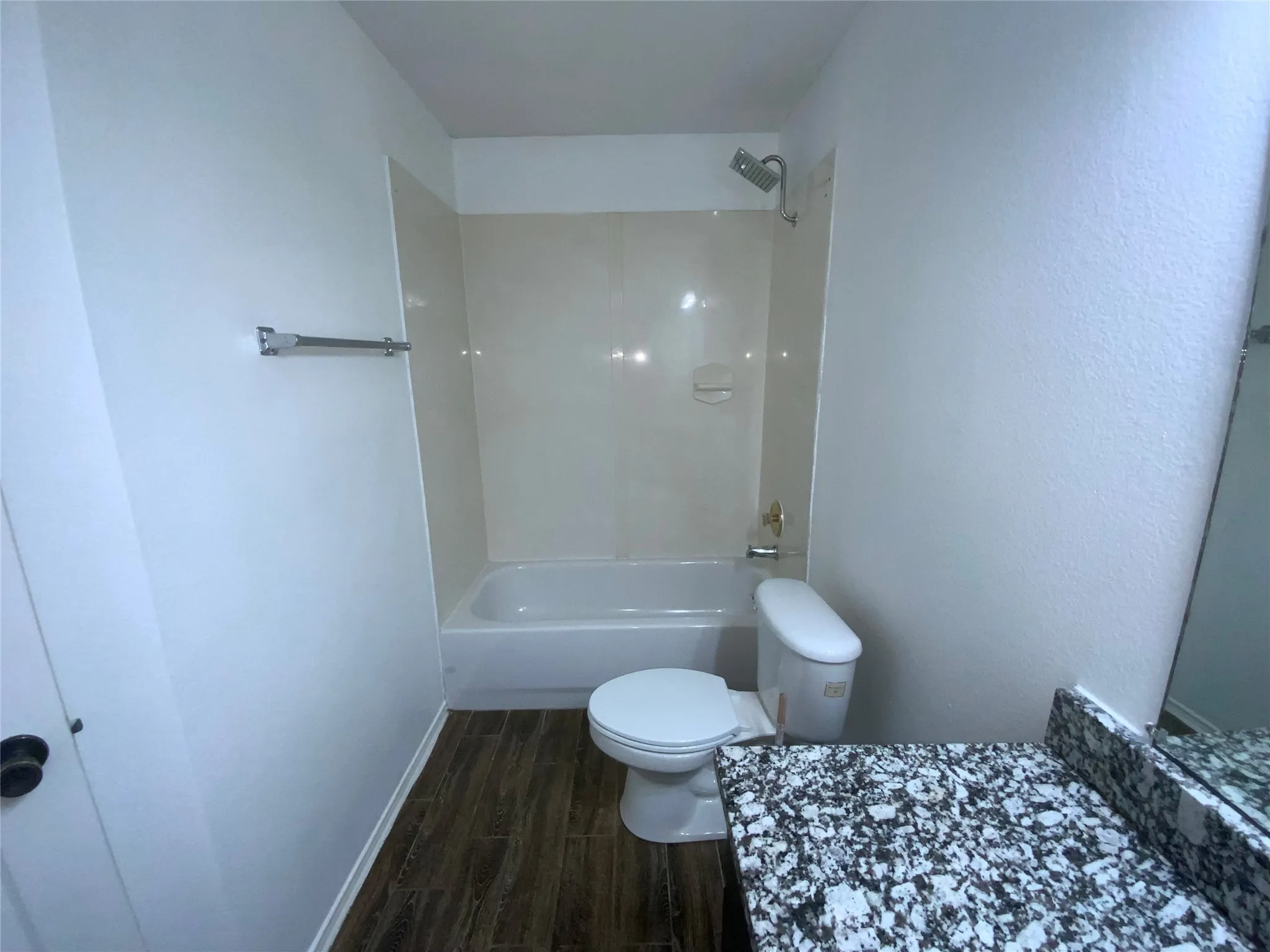 Bathroom featuring a white bathtub, shower with a rainfall showerhead, and wood-finish flooring