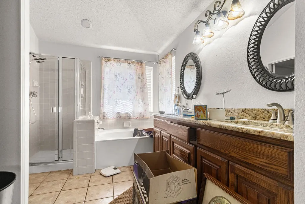 Dual vanity with undermount sinks, tile flooring, glass-enclosed shower, and built-in tub