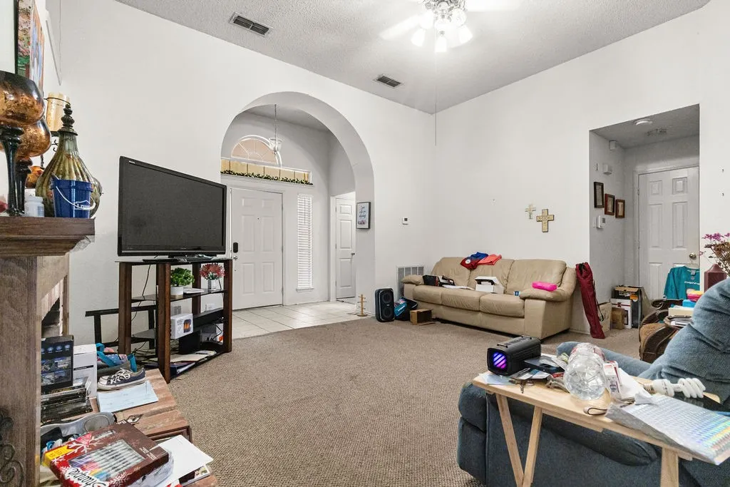 Arched entryway with transom window, ceiling fan, carpeted flooring, and white interior doors