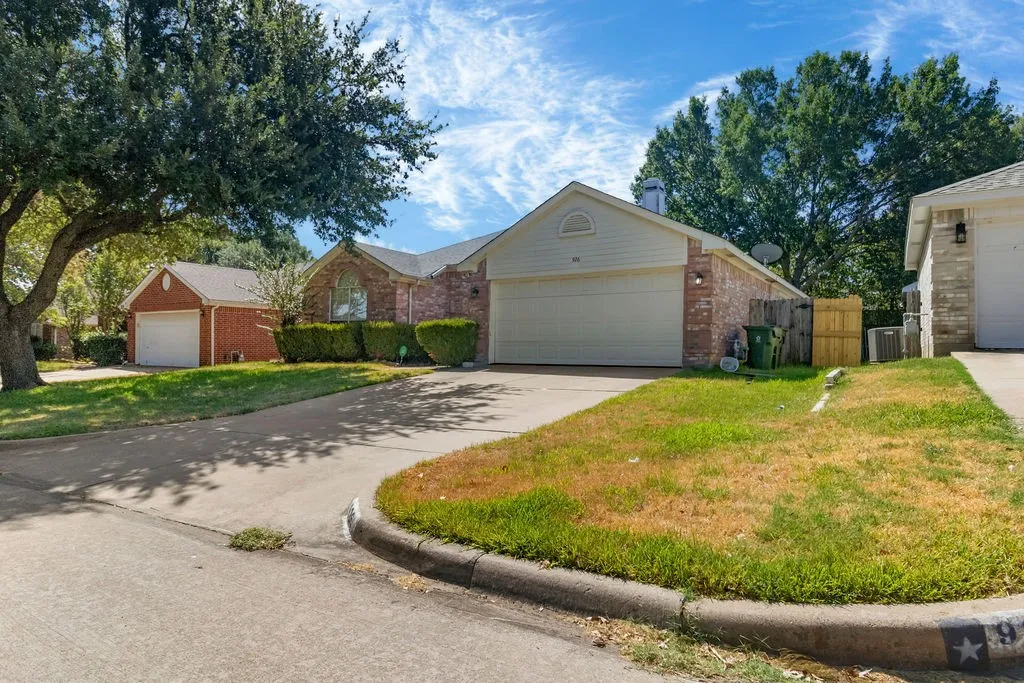 Brick exterior with a two-car garage, established front landscaping, an additional detached garage, and a concrete driveway