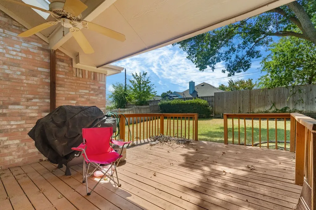 Covered patio featuring a ceiling fan, wood-finish decking, and a brick exterior wall