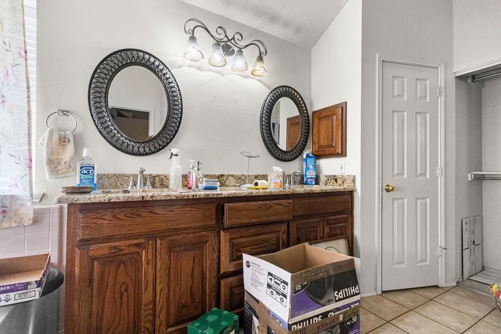 Double vanity with wood cabinetry, granite-style countertop, and integrated sinks