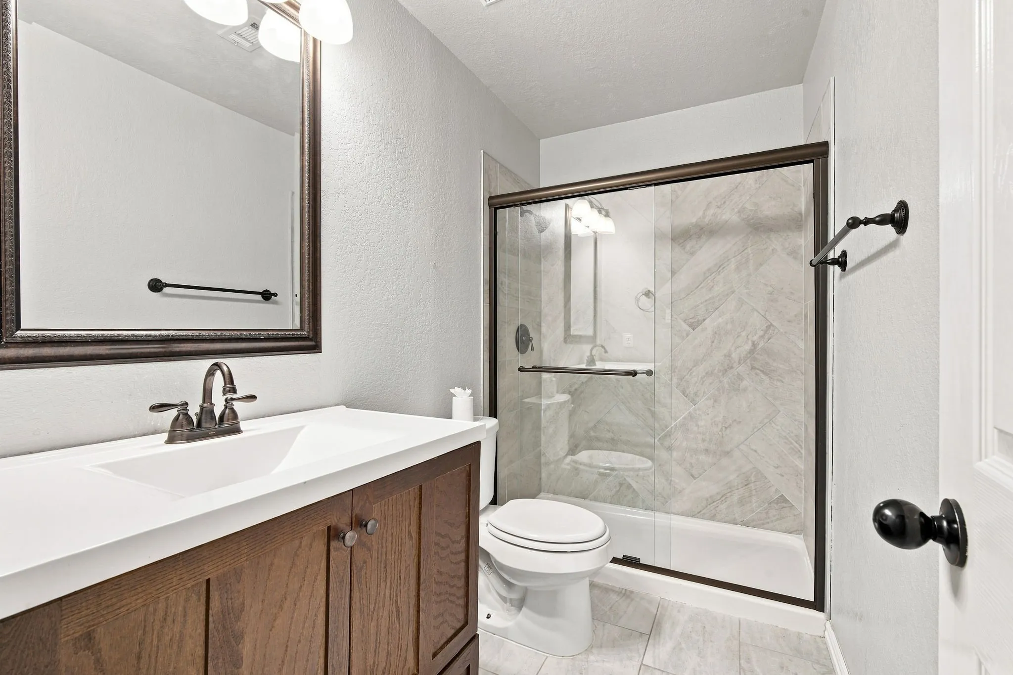 Charming bath featuring a vanity with an integrated sink, a warm bronze-finish faucet, and a coordinating mirror.
