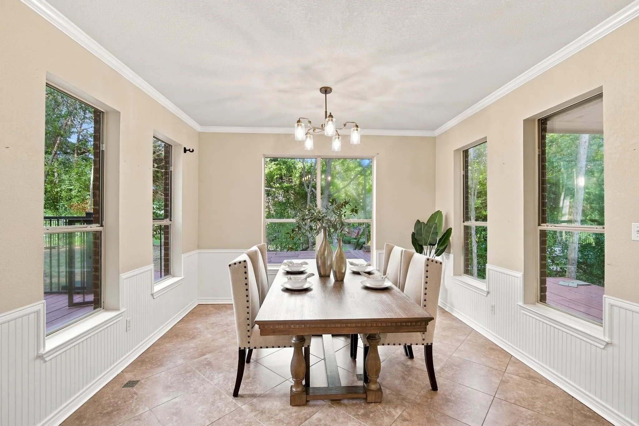Elegant dining area featuring classic beadboard wainscoting, crown molding, and plenty of natural light from multiple windows.