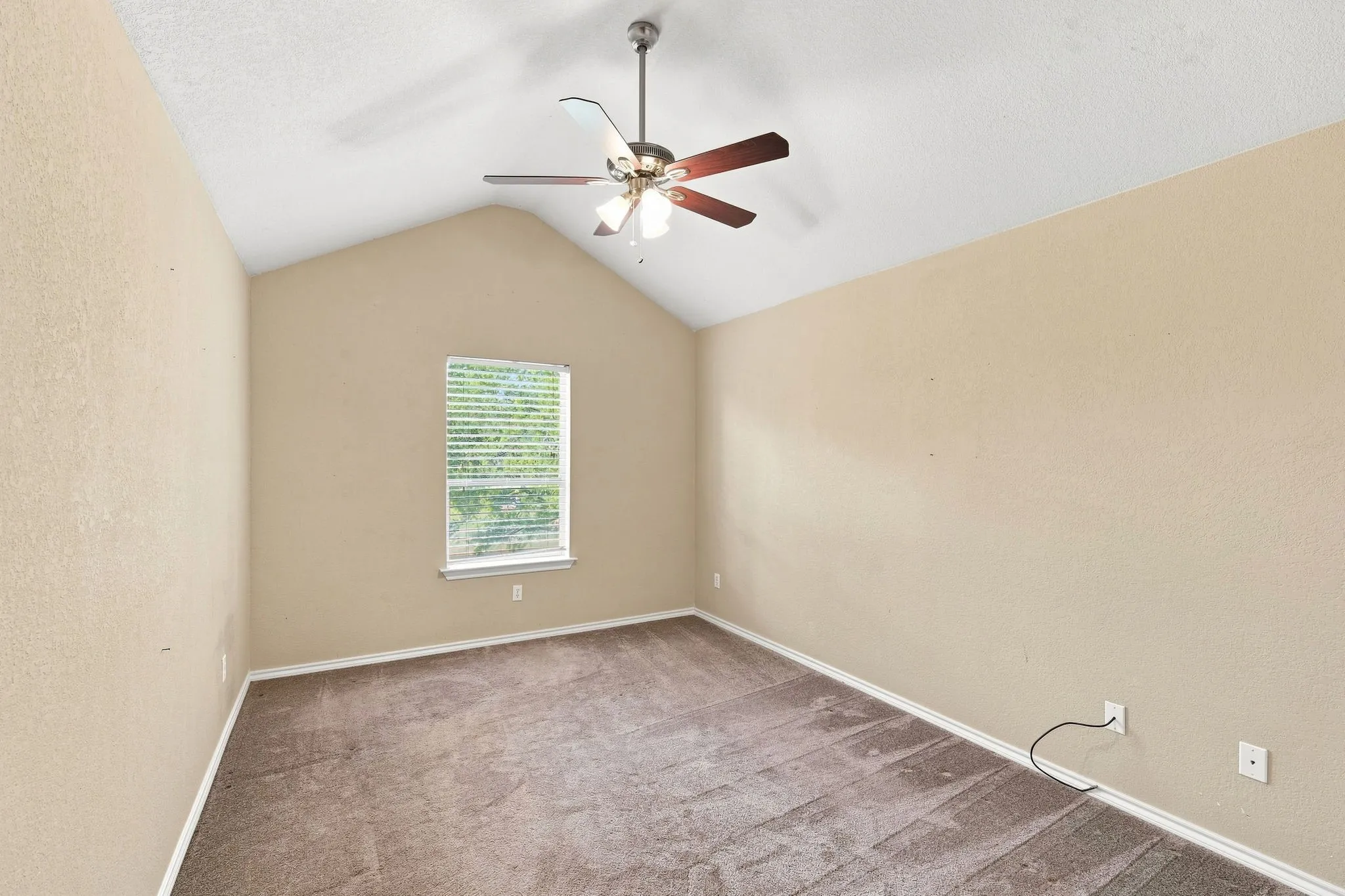 Bright room with a vaulted ceiling, ceiling fan, and calming neutral tones, ready for your personal touch.