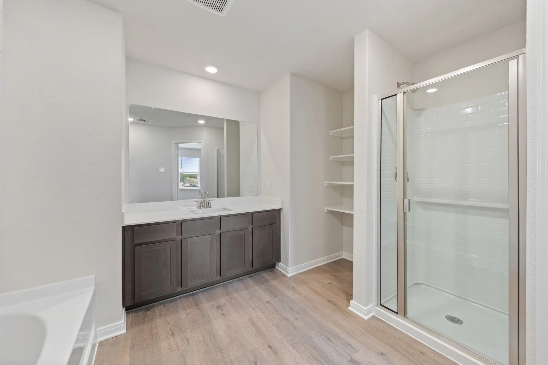 Bathroom featuring vanity, wood finished floors, a stall shower, and recessed lighting