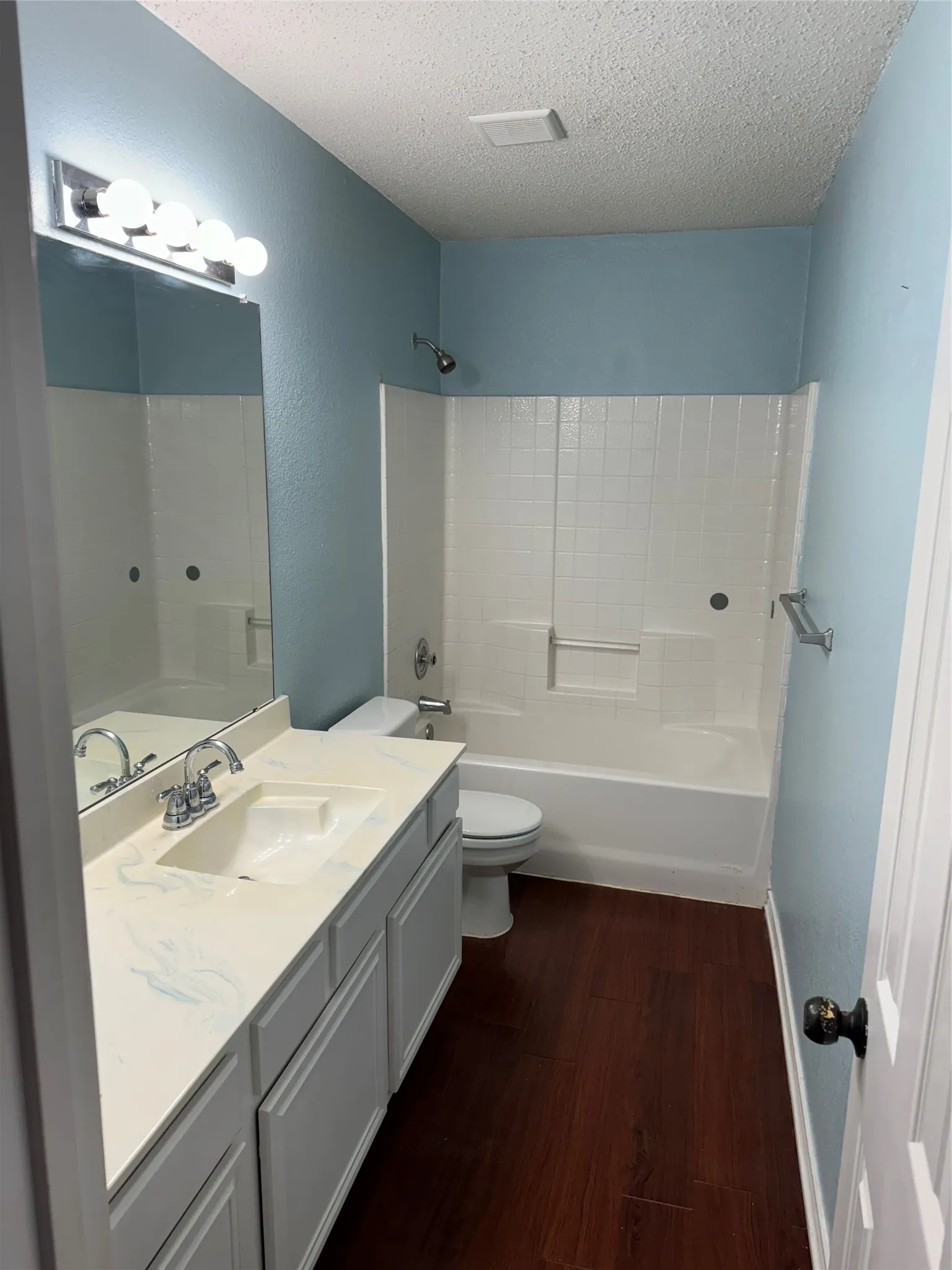 Full bathroom featuring vanity, hardwood / wood-style floors, bathtub / shower combination, toilet, and a textured ceiling