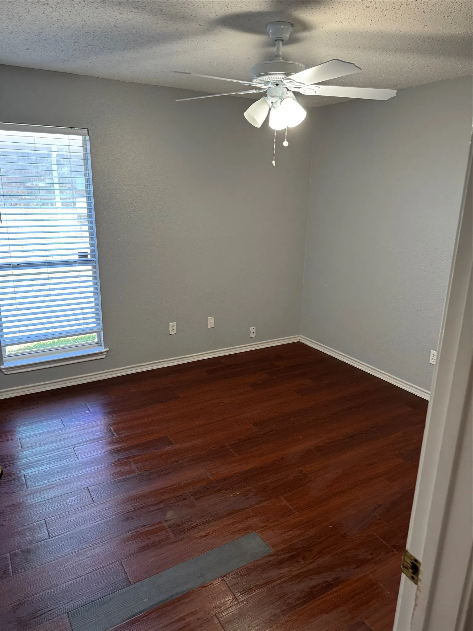Empty room featuring dark hardwood / wood-style flooring, ceiling fan, and a textured ceiling