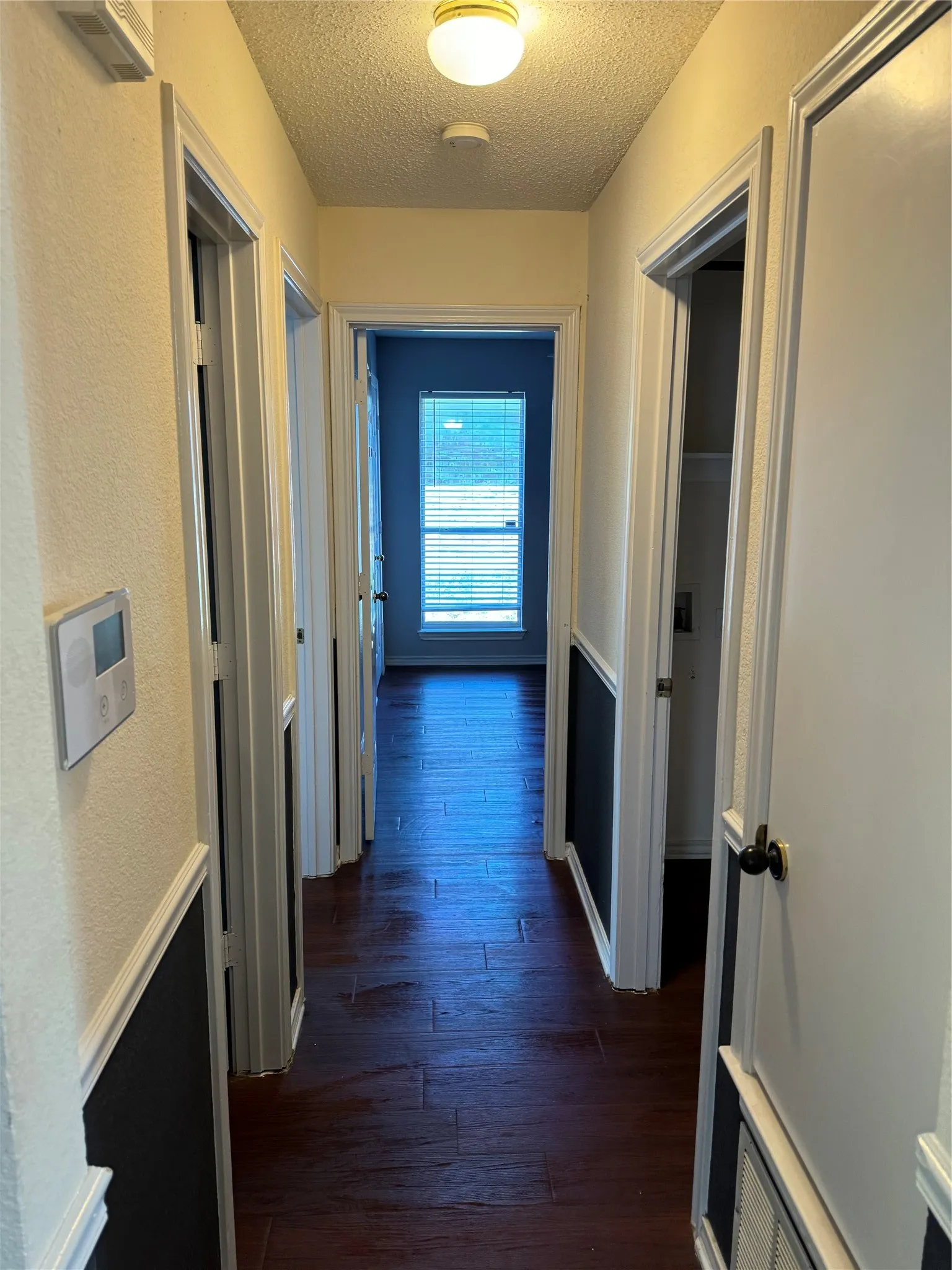 Corridor with dark hardwood / wood-style floors and a textured ceiling