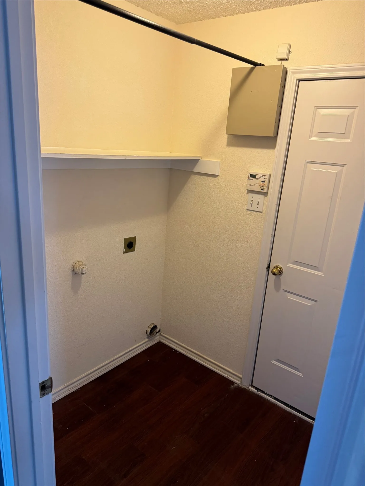 Clothes washing area with hookup for an electric dryer, dark hardwood / wood-style flooring, and a textured ceiling