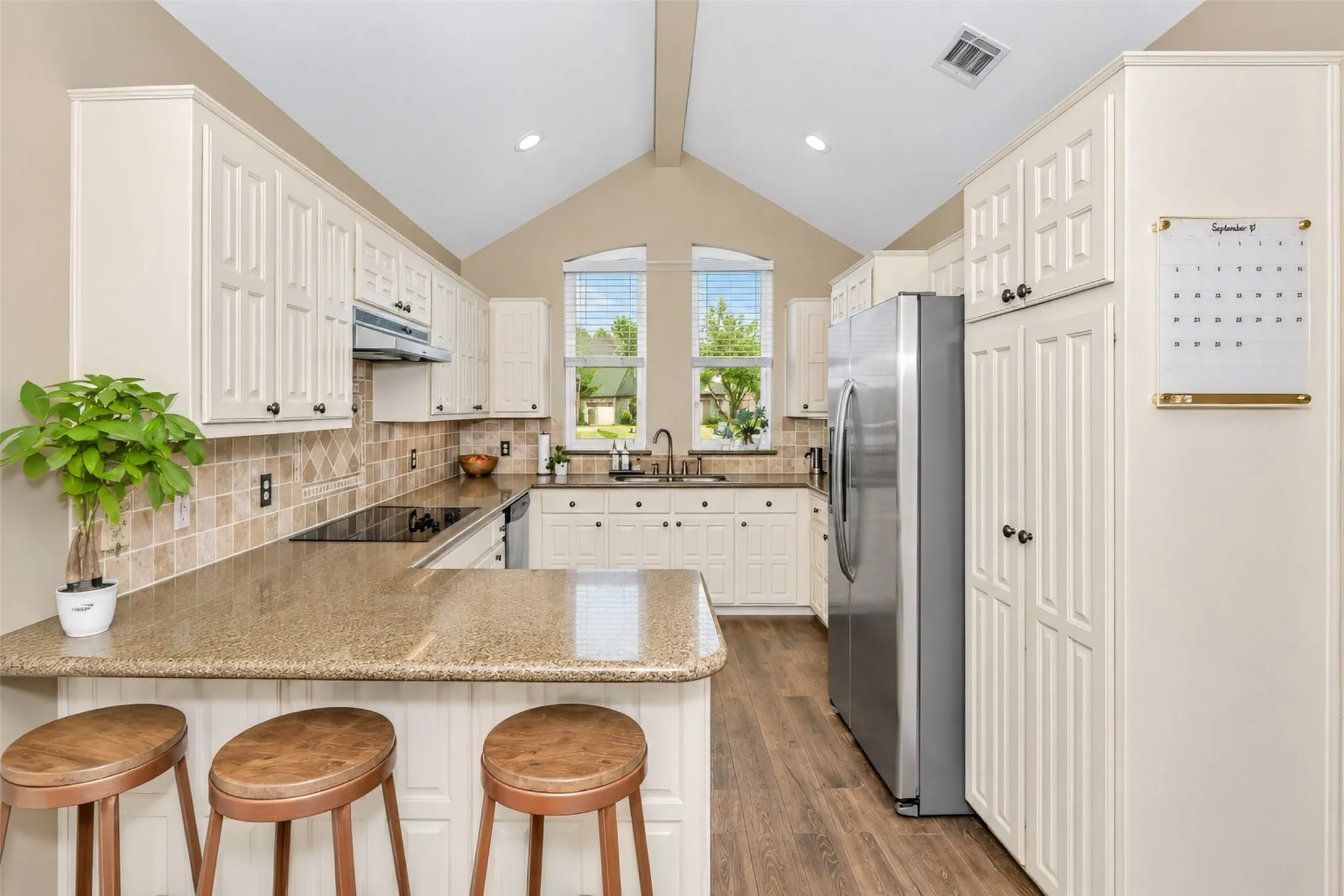 Impressive kitchen with custom cabinetry, vaulted ceiling, millwork and a breakfast bar.