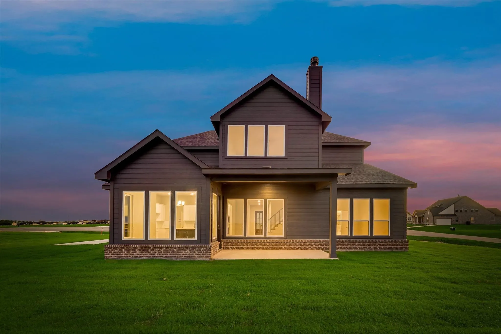 Two-story exterior with a covered patio, dark siding, and brick accents