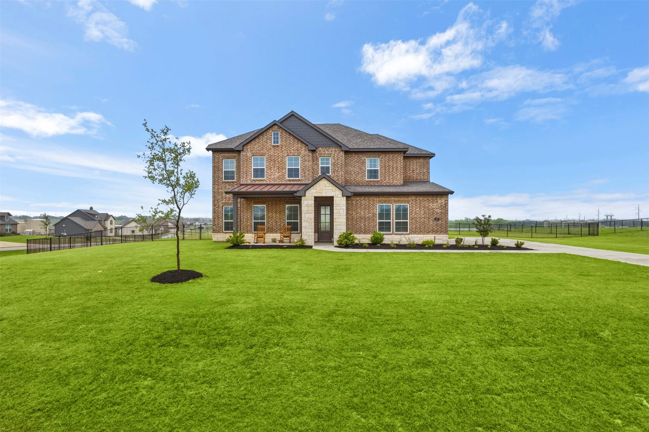 Brick exterior with stone accents, covered front porch, and a concrete driveway