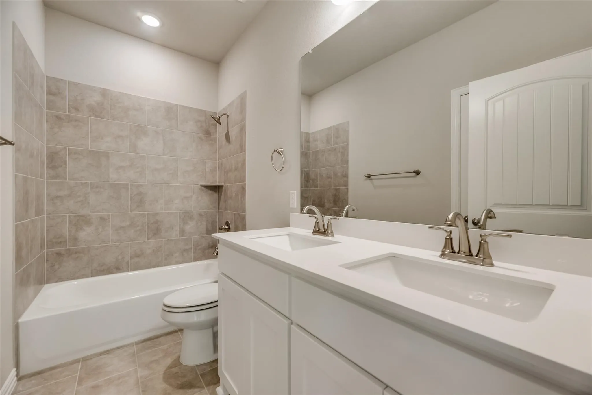 Double vanity with white cabinetry, integrated sinks, brushed nickel fixtures, and a spacious mirror