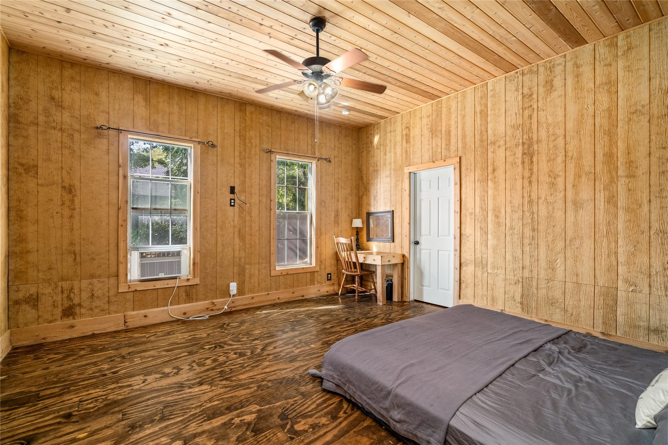 Wood-paneled walls and ceiling with a ceiling fan