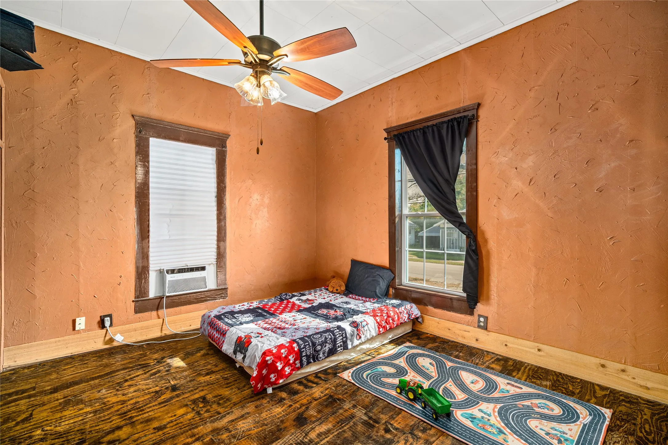Textured wall finish, wood-finish flooring, ceiling fan with lighting, and two windows