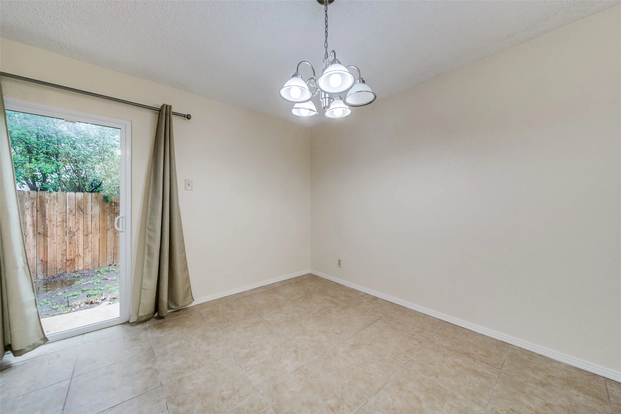 Tile flooring, sliding glass door, overhead lighting fixture, and a wooden fence