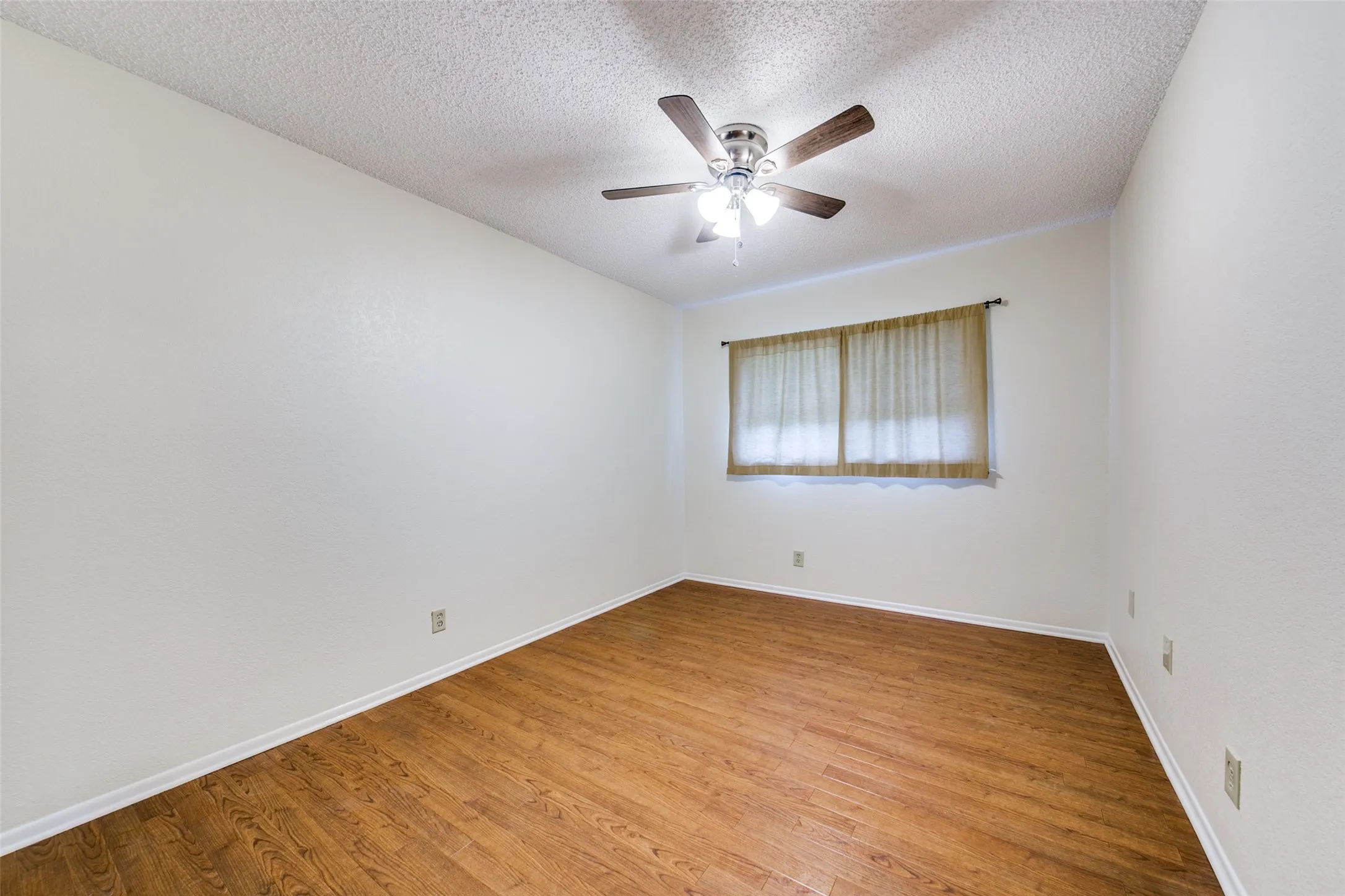 Wood-finish flooring, ceiling fan with integrated lighting, and a single window
