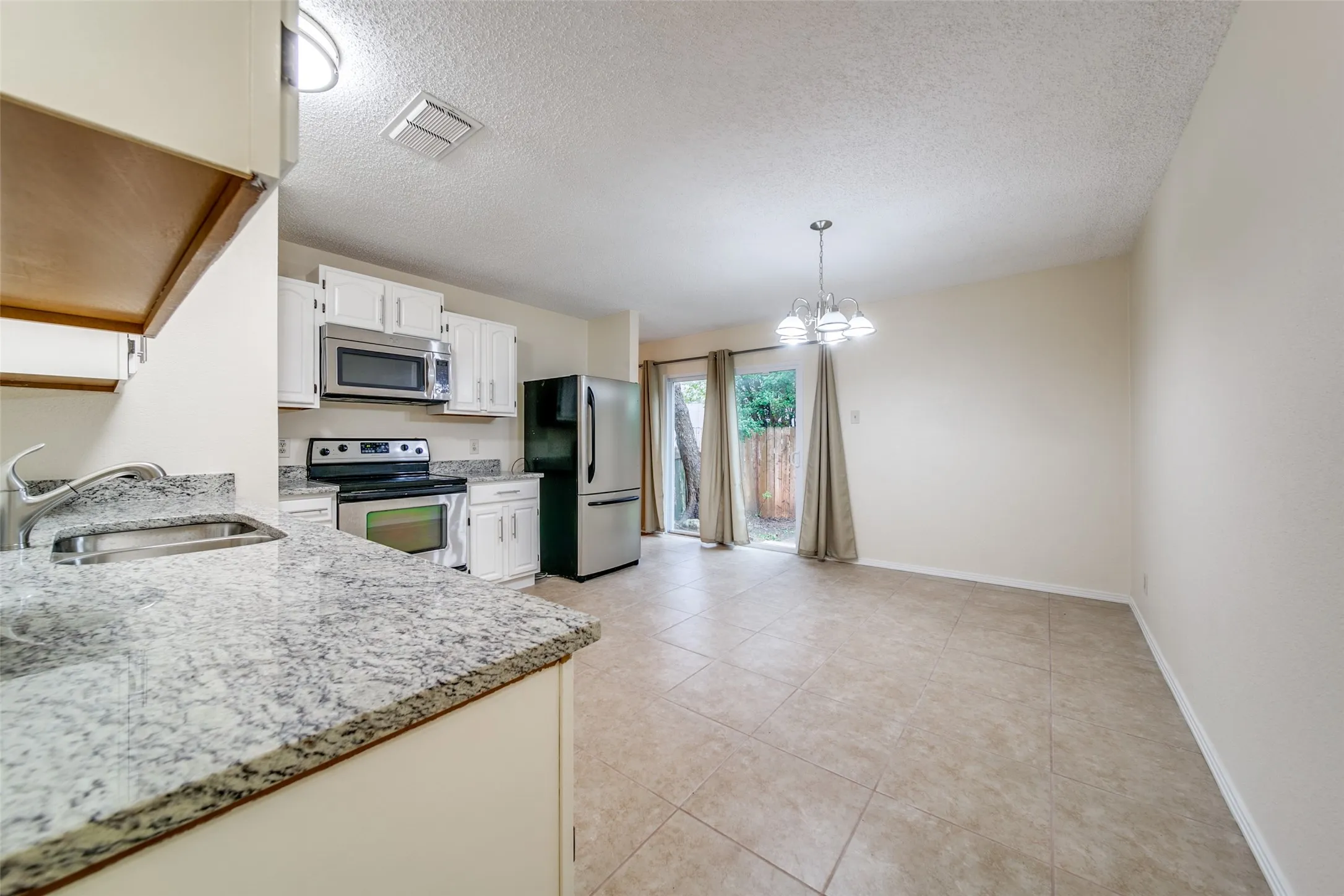 Kitchen featuring white cabinetry, stainless steel appliances, granite countertops, and a tile floor