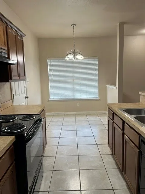 Kitchen featuring tile flooring, dark wood-finish cabinetry, and a window with blinds