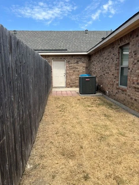 Brick exterior with a shingle roof and a privacy fence
