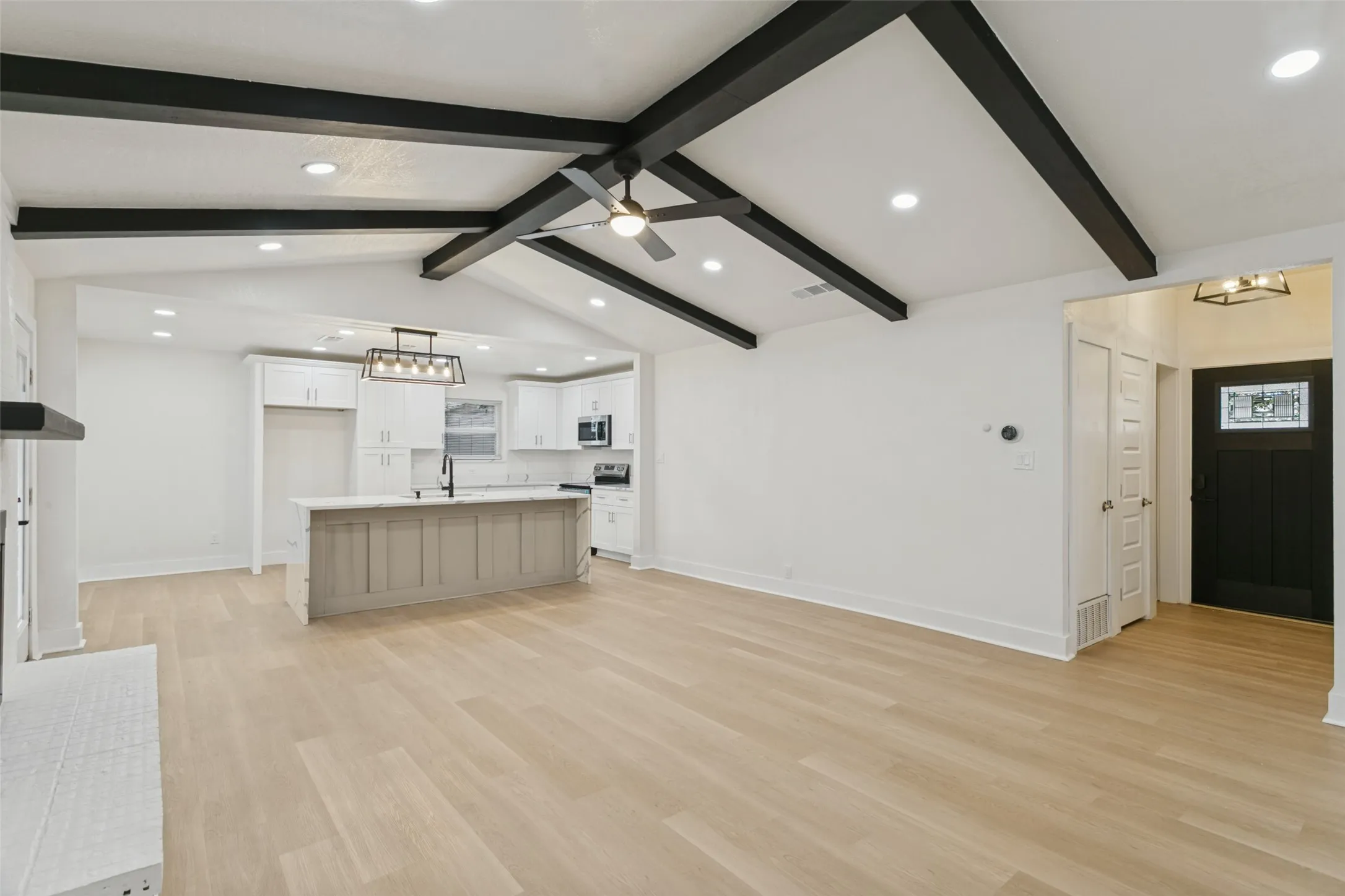 Vaulted ceiling with exposed beams, wood-finish flooring, recessed lighting, kitchen island with built-in cabinetry, and a modern ceiling fan