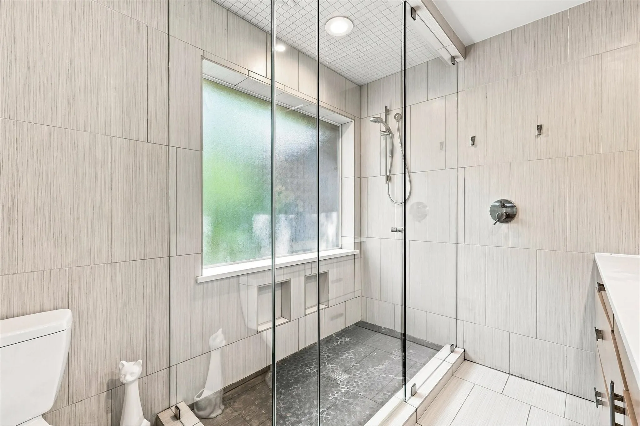 Glass-enclosed shower with a handheld shower fixture, built-in shower niches, and recessed​​‌​​​​‌​​‌‌​‌‌​​​‌‌​‌​‌​‌​​​‌​​ lighting