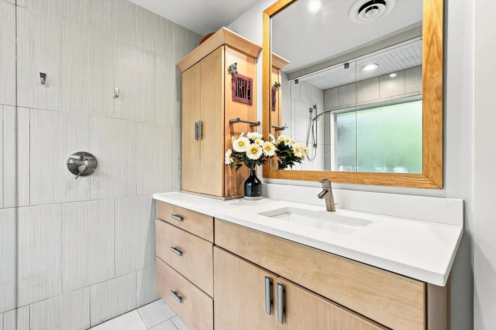 Uniquely designed primary sink and organization includes quartzite countertops and hidden electrical outlets inside of cabinets. Small handheld styling tools are always out of sight.