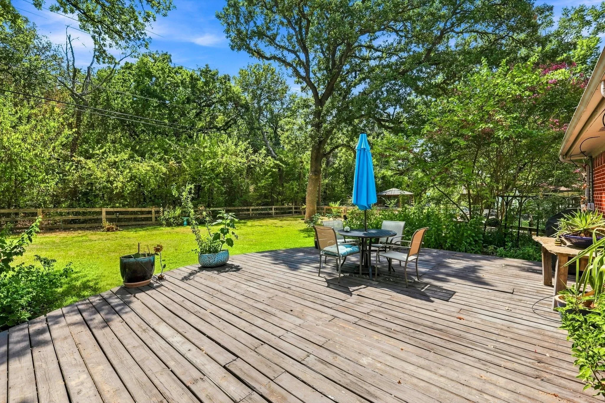 Step outside to the expansive wood deck with a manicured lawn, mature trees, and lush landscaping.