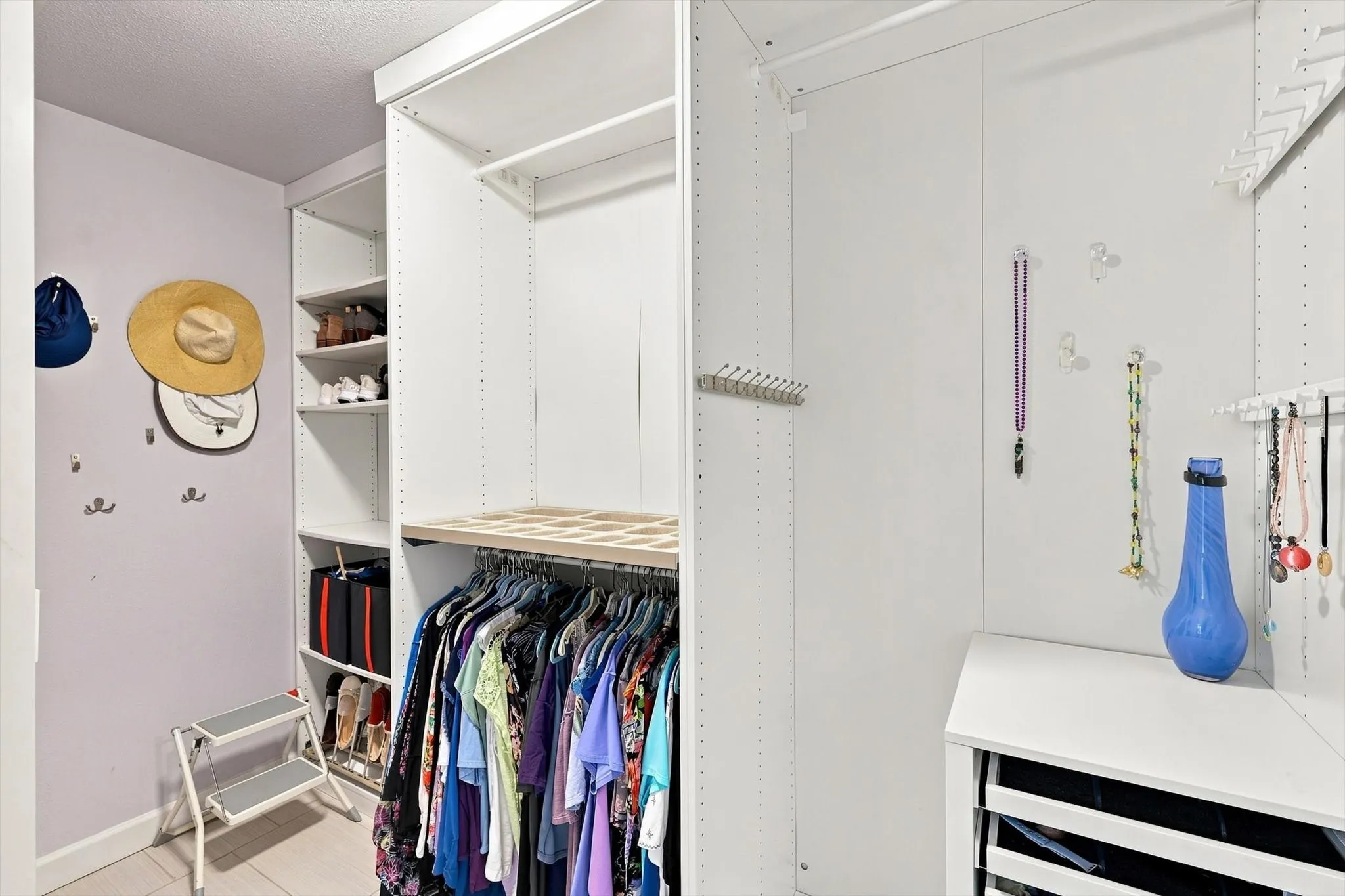 Partial view of primary walk-in closet. Closet organization system keeps everything nice and tidy!