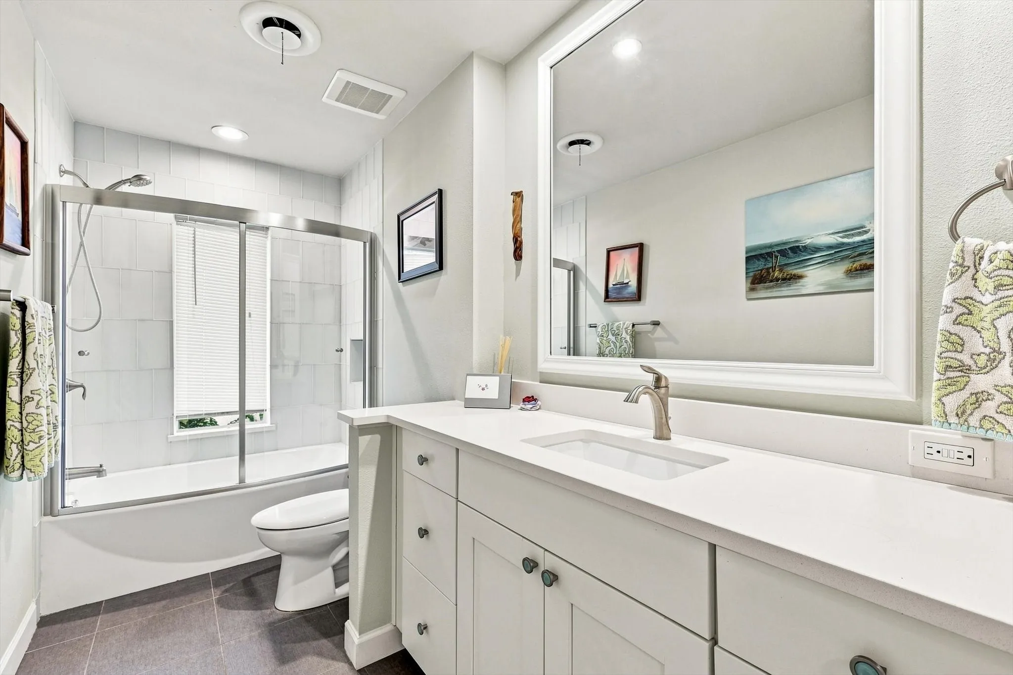 Secondary bathroom has white shaker-style cabinets with quartzite countertops, and a state-of-the-art curved glass shower enclosure.