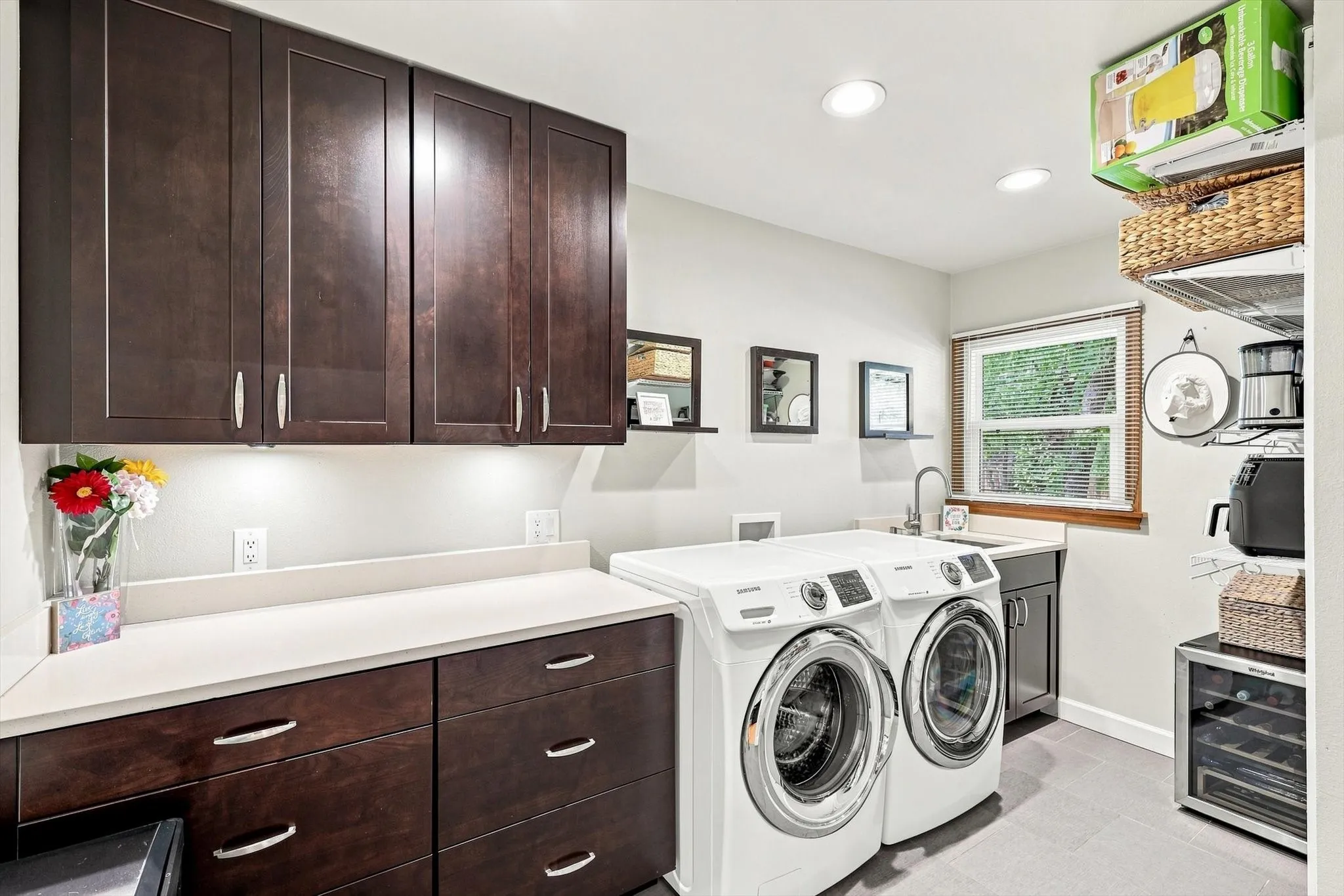 Incredible laundry room has plenty of cabinets, countertops, utility sink, and Elfa pantry shelving.