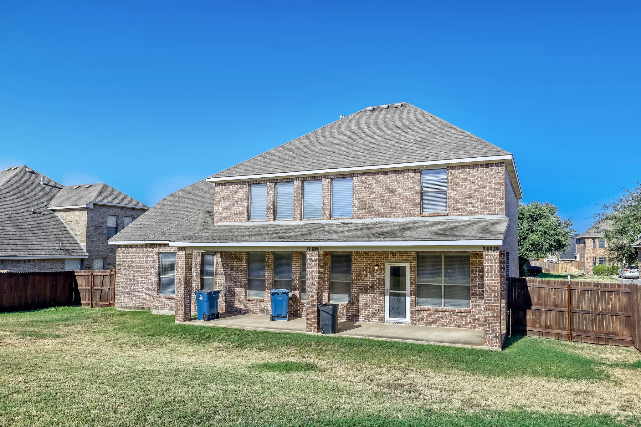 Brick exterior with a shingle roof and a covered patio