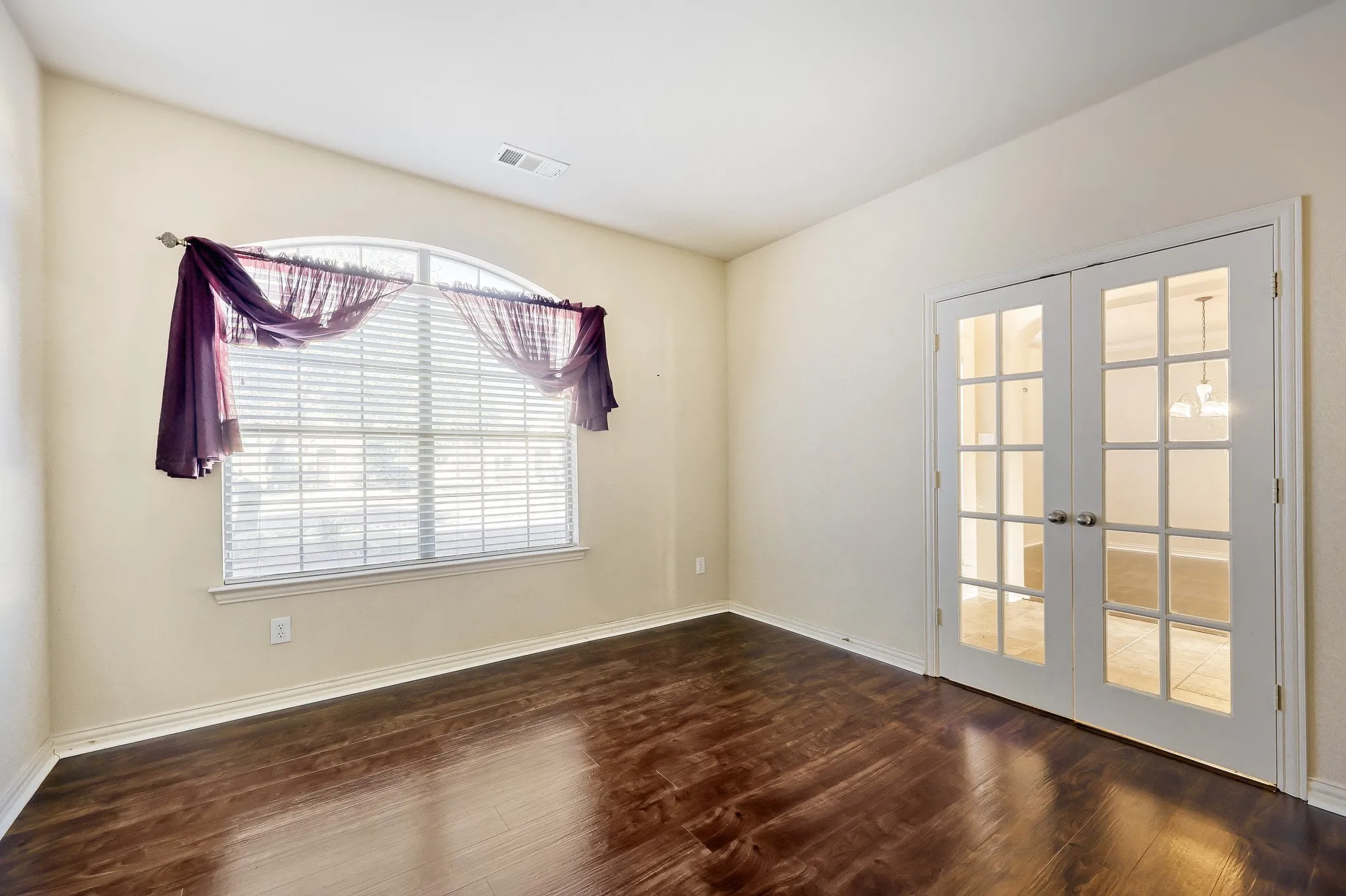 Vaulted ceiling, arched window, wood-finish flooring, white trim, and French doors