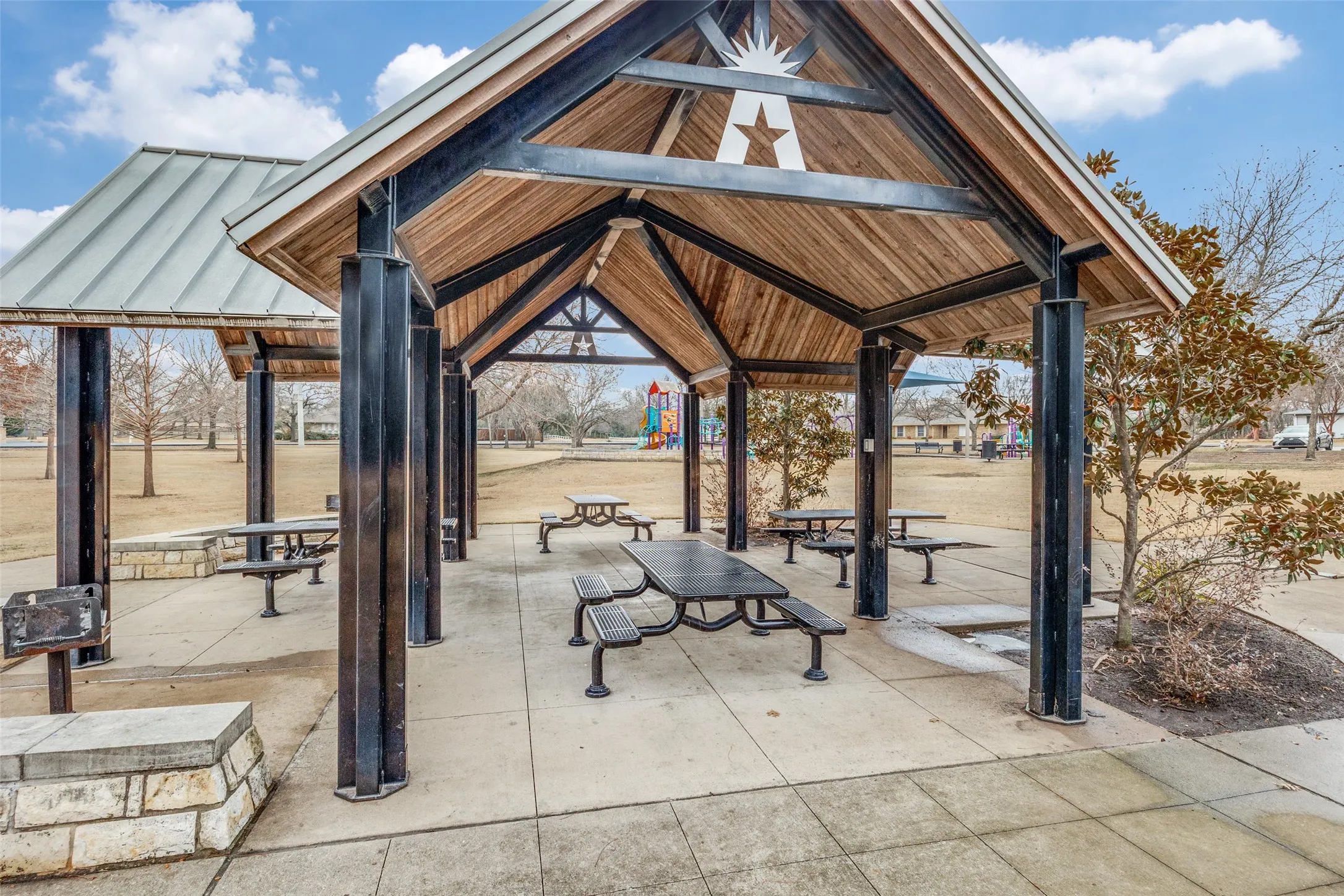 Shaded outdoor pavilion featuring a wood-panel ceiling, metal roof, and concrete flooring